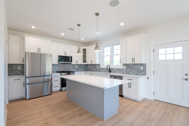 kitchen with stainless steel appliances, light wood-style floors, white cabinets, and a sink