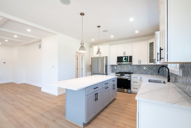 kitchen with light wood-style flooring, a center island, a sink, stainless steel appliances, and backsplash