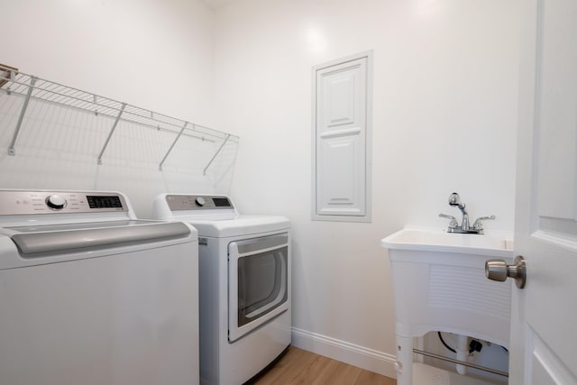 laundry room featuring light wood-style flooring, a sink, laundry area, independent washer and dryer, and baseboards