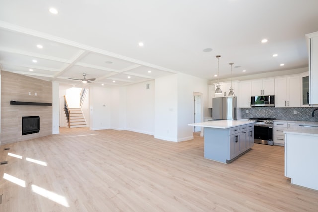 kitchen with stainless steel appliances, open floor plan, light countertops, a center island, and tasteful backsplash