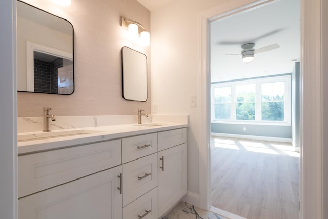 full bathroom featuring double vanity, a ceiling fan, baseboards, and a sink