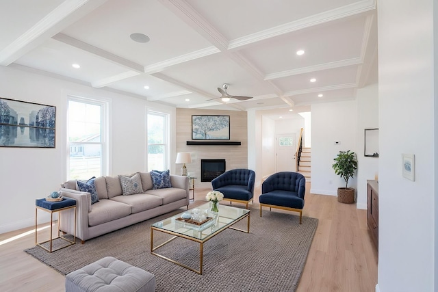 living area featuring coffered ceiling, baseboards, light wood-style floors, beamed ceiling, and a glass covered fireplace