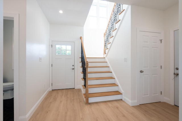 entryway featuring light wood-style floors, baseboards, and stairway