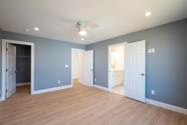 unfurnished bedroom with light wood-style flooring, baseboards, a walk in closet, and recessed lighting