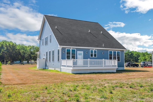 back of property featuring a shingled roof, a lawn, and a wooden deck