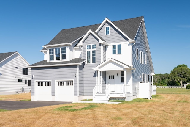 view of front facade with a garage, roof with shingles, driveway, and a front lawn