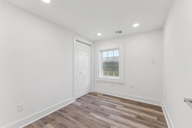 empty room with light wood-style floors, recessed lighting, visible vents, and baseboards