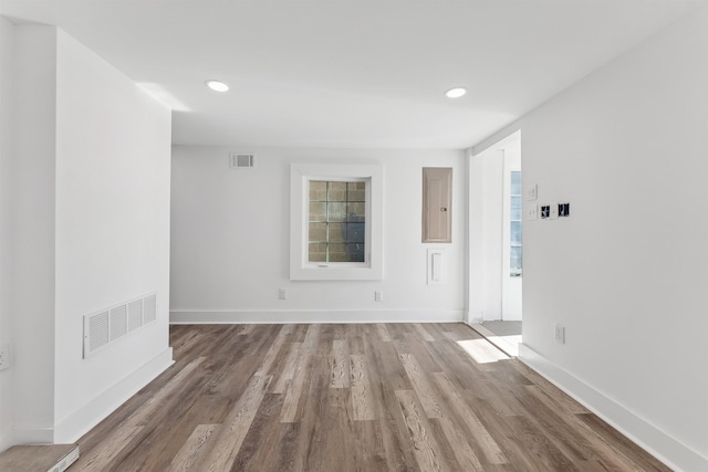 empty room with recessed lighting, visible vents, light wood-type flooring, electric panel, and baseboards