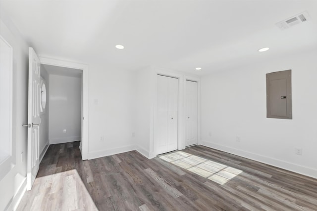 unfurnished bedroom featuring dark wood-type flooring, electric panel, visible vents, and baseboards