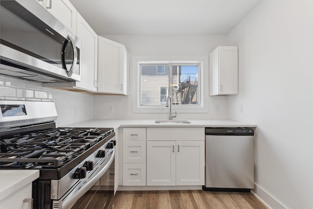 kitchen with stainless steel appliances, light countertops, white cabinetry, and a sink