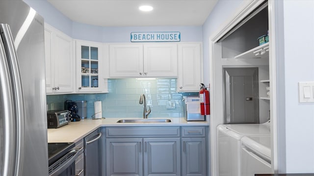 351 96th St Unit 209, Stone Harbor, NJ 08247 - kitchen featuring appliances with stainless steel finishes, a sink, washer and clothes dryer, decorative backsplash, and white cabinets