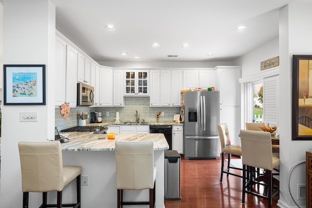 kitchen featuring a kitchen bar, appliances with stainless steel finishes, white cabinets, and sink