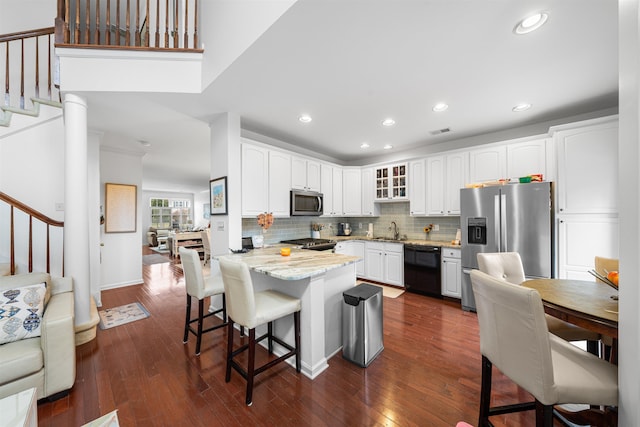 kitchen featuring white cabinetry, sink, light stone countertops, a breakfast bar area, and appliances with stainless steel finishes