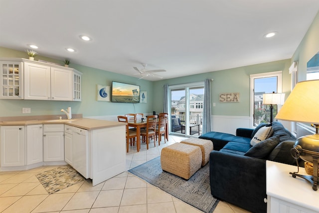 kitchen with dishwasher, sink, white cabinets, light tile patterned floors, and kitchen peninsula