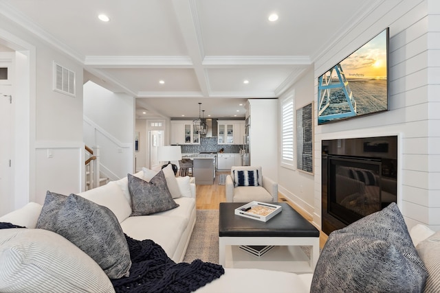 living room with ornamental molding, coffered ceiling, beam ceiling, a fireplace, and hardwood / wood-style floors