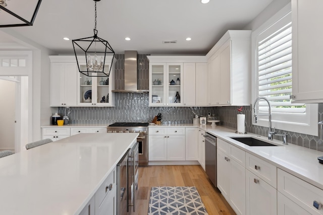 kitchen with white cabinets, wall chimney exhaust hood, and sink