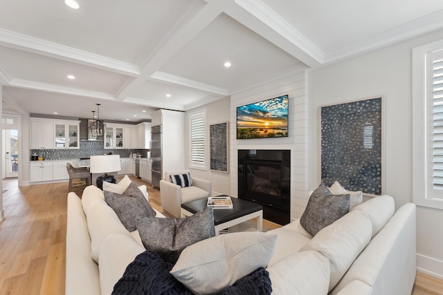 living room with coffered ceiling, crown molding, light hardwood / wood-style floors, a fireplace, and beam ceiling