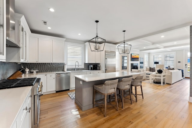 kitchen featuring beamed ceiling, premium appliances, white cabinetry, and a kitchen island