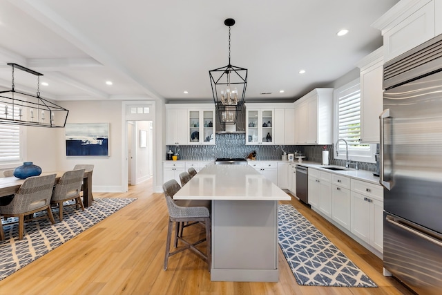 kitchen with white cabinetry, hanging light fixtures, a kitchen island, and stainless steel appliances