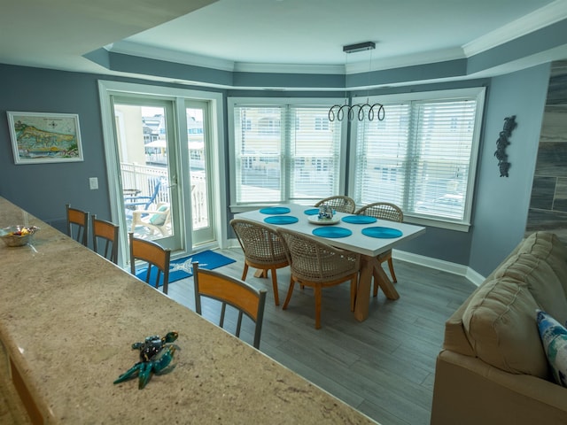 dining space featuring wood finished floors, ornamental molding, baseboards, and plenty of natural light