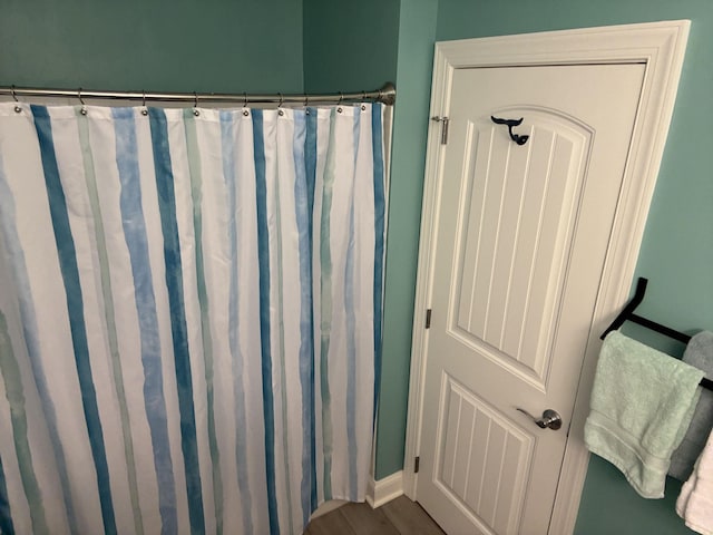 full bathroom featuring baseboards, a shower with shower curtain, and wood finished floors