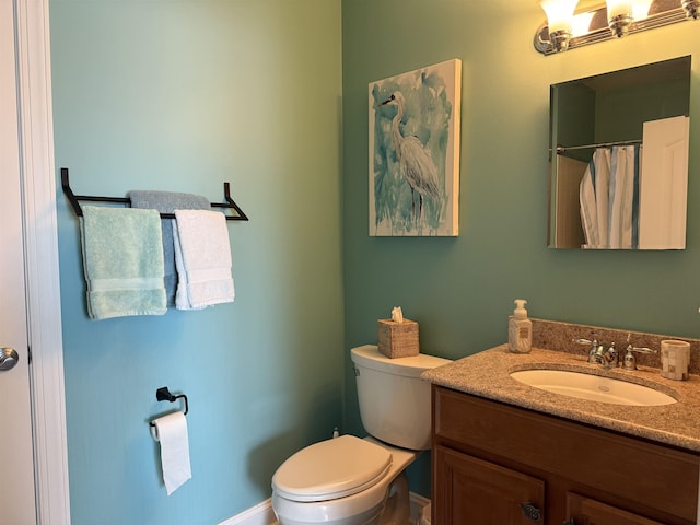 bathroom with toilet, vanity, and baseboards
