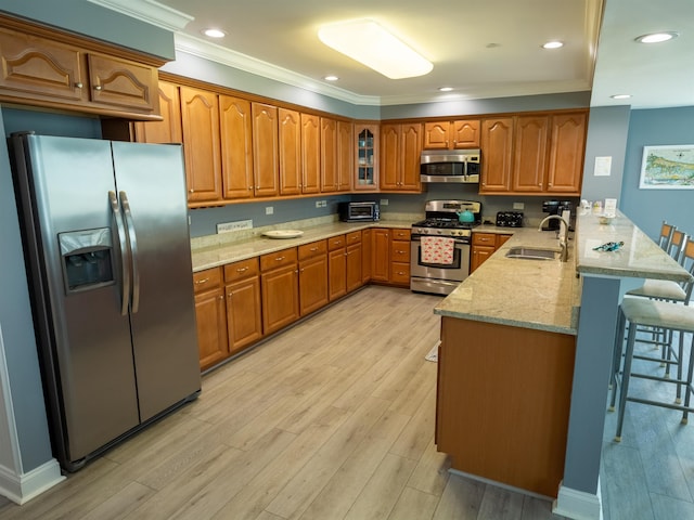 kitchen featuring a peninsula, appliances with stainless steel finishes, brown cabinets, and a sink