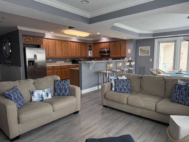 living room with recessed lighting, a raised ceiling, visible vents, light wood-style floors, and crown molding