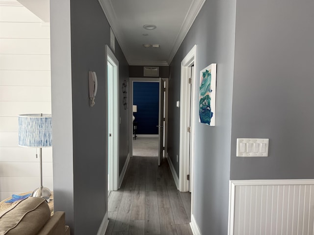 corridor featuring baseboards, crown molding, wood finished floors, and visible vents