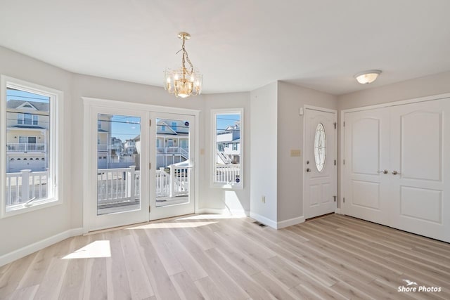 entryway with light wood-type flooring, baseboards, and an inviting chandelier