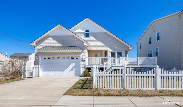 view of front of house featuring a fenced front yard, covered porch, concrete driveway, and a garage