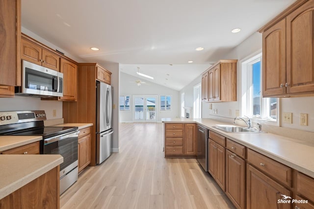 kitchen featuring ceiling fan, light countertops, light wood-style flooring, appliances with stainless steel finishes, and a sink