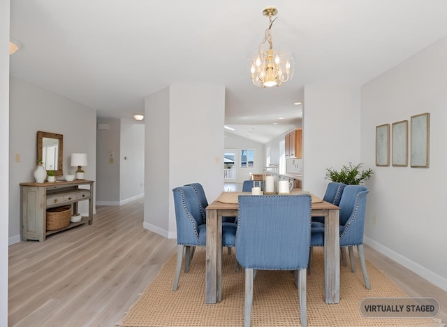 dining room featuring baseboards, an inviting chandelier, light wood-style flooring, and vaulted ceiling