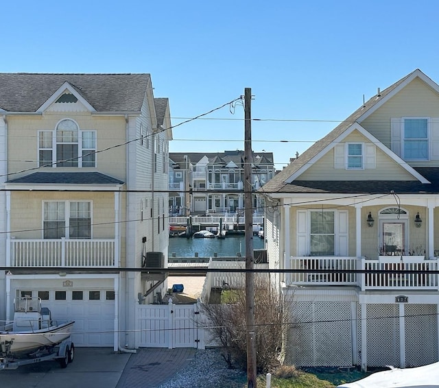 view of side of home with a shingled roof, fence, a water view, central air condition unit, and an attached garage