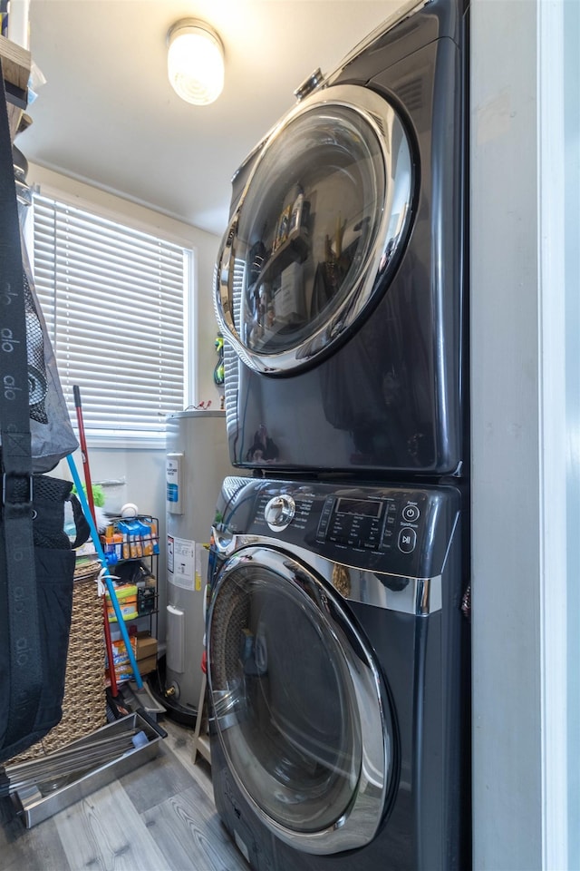 laundry room featuring stacked washer / drying machine, hardwood / wood-style flooring, and electric water heater