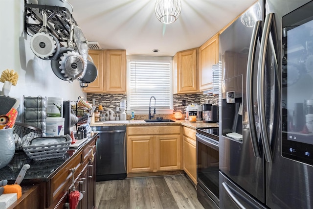 kitchen with hardwood / wood-style flooring, light stone countertops, decorative backsplash, appliances with stainless steel finishes, and sink