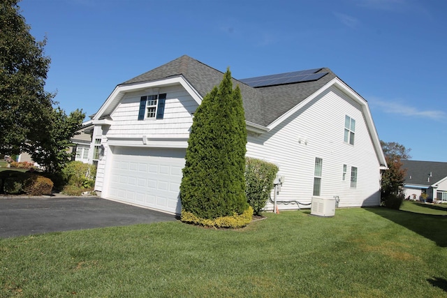 view of home's exterior with a yard, a garage, and solar panels