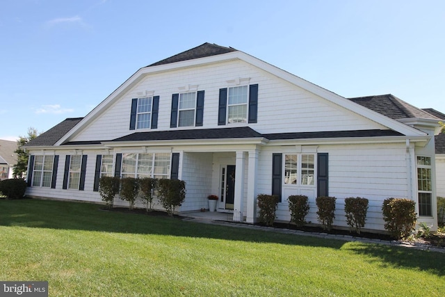 view of front facade with a shingled roof and a front lawn