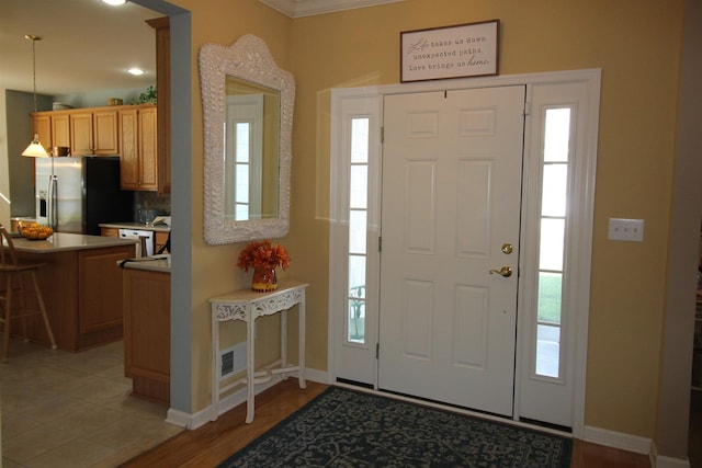 foyer entrance featuring crown molding and light wood-type flooring