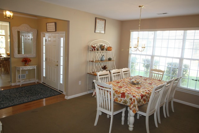 dining space with dark hardwood / wood-style floors and an inviting chandelier