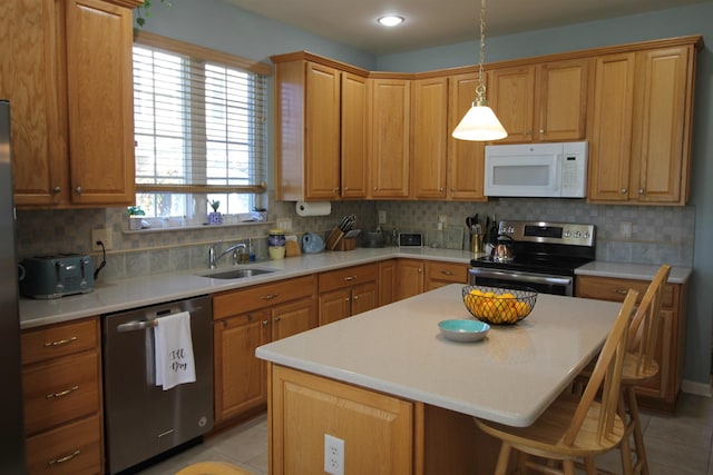 kitchen featuring light tile patterned floors, stainless steel appliances, a sink, light countertops, and a kitchen bar