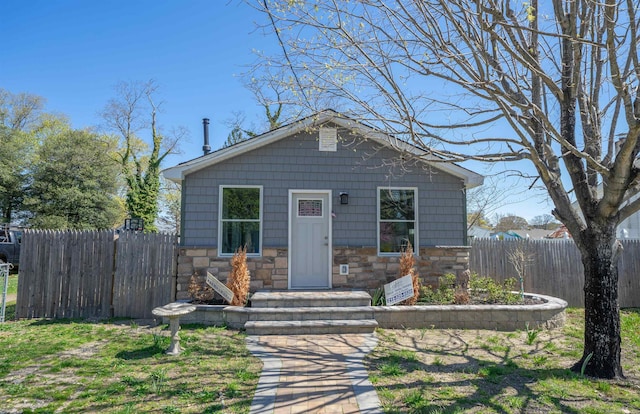 bungalow featuring fence and stone siding