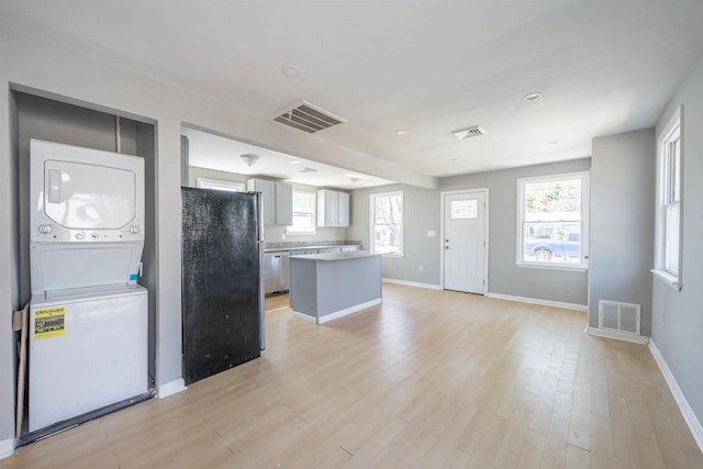 kitchen with freestanding refrigerator, visible vents, and stacked washer / dryer
