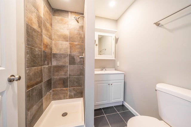 bathroom featuring vanity, a tile shower, toilet, and tile patterned flooring