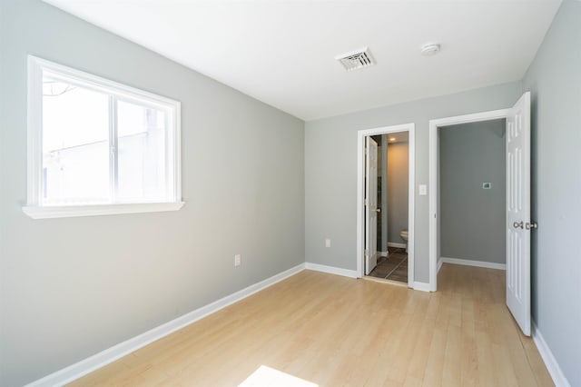 unfurnished bedroom with light wood-type flooring, visible vents, and baseboards