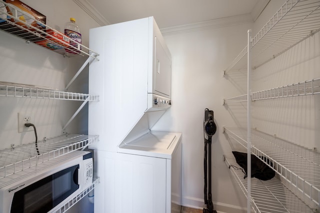 laundry area with laundry area, ornamental molding, and stacked washer and dryer