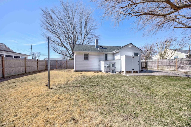 rear view of house featuring a fenced backyard, a yard, and a chimney