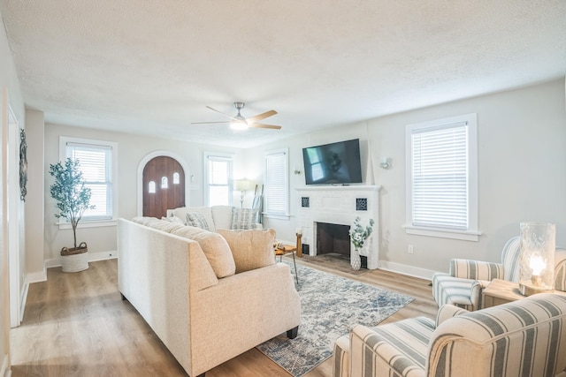 6110 Seaview Ave, Wildwood Crest, NJ 08260 - living room featuring a ceiling fan, light wood-style flooring, a textured ceiling, a fireplace, and arched walkways