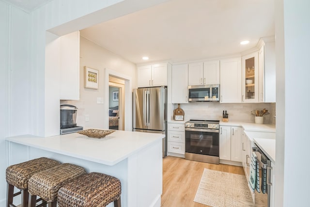 6110 Seaview Ave, Wildwood Crest, NJ 08260 - kitchen with appliances with stainless steel finishes, a kitchen bar, light wood-style flooring, a peninsula, and decorative backsplash