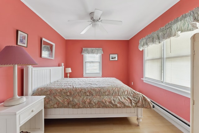 bedroom with a baseboard radiator, hardwood / wood-style floors, and ceiling fan